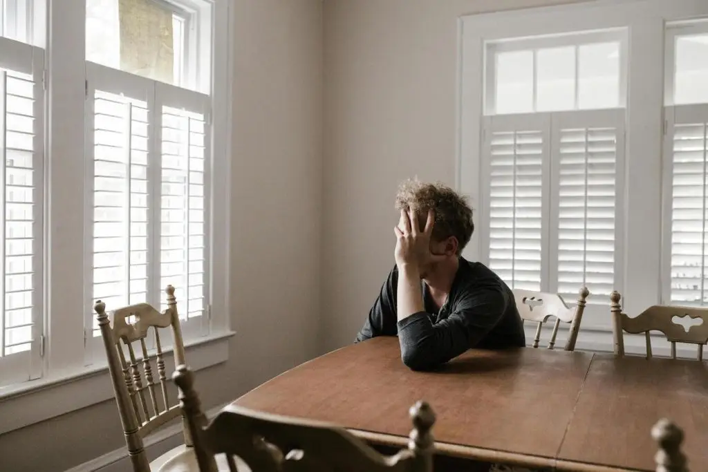 Man sitting at a table holding his head