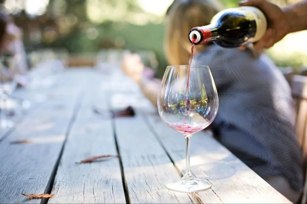 A person pouring a glass of red wine