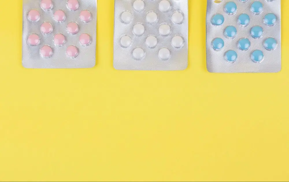 Three blister packs with pink, white, and blue pills side by side