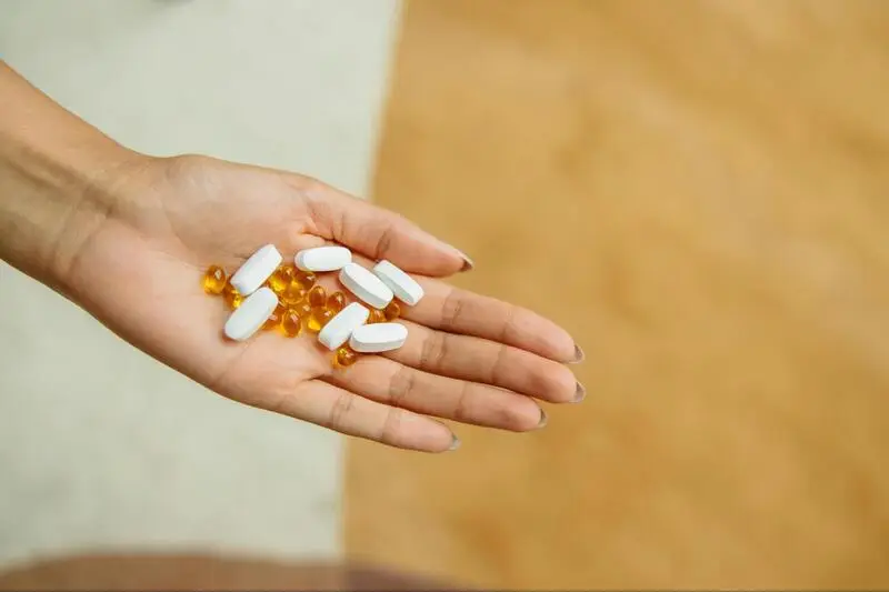 A close-up of a hand holding two different types of medication pills