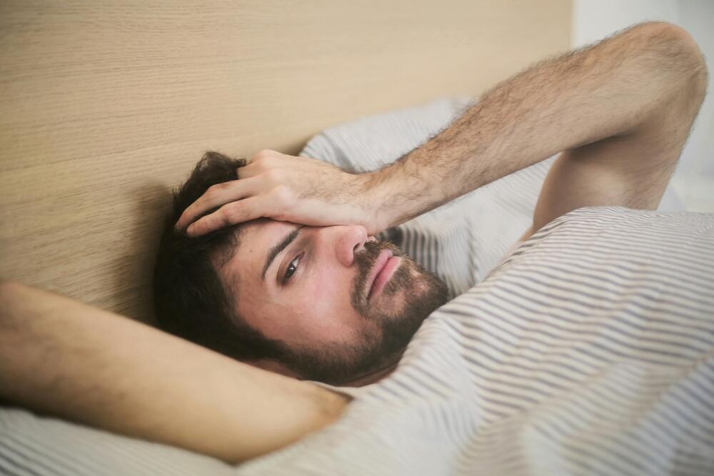 A sleepy man laying in bed - does tramadol make you sleepy